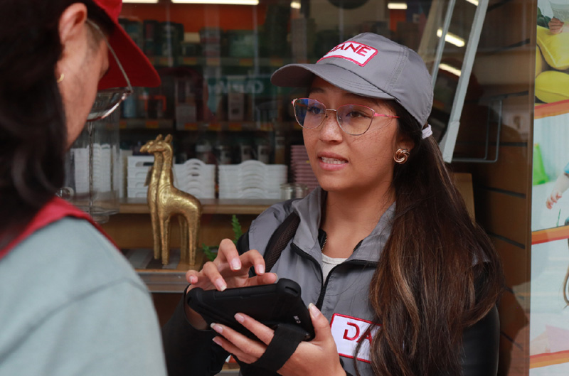 Encuestadora hablando con una persona, mientras en una tablet información